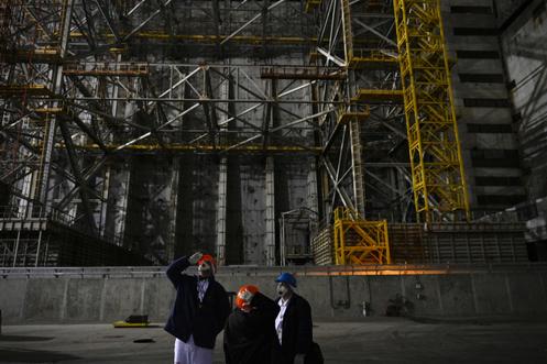 Em frente ao sarcófago que cobre o quarto reator destruído sob o novo arco de contenção, na usina nuclear de Chernobyl (Ucrânia), 9 de abril de 2026.