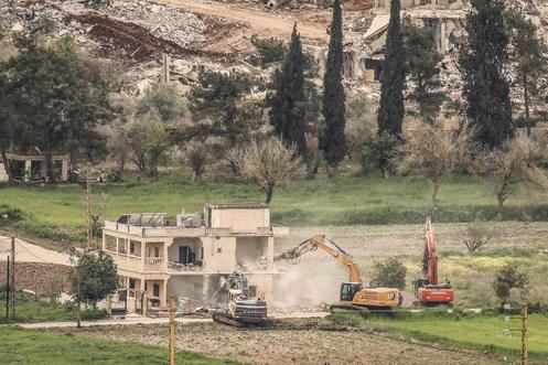 Des excavatrices israéliennes démolissent un bâtiment dans le sud du Liban, vues du côté israélien de la frontière, le 15 avril 2026.