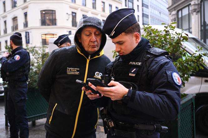 Um policial examina a carteira de identidade de um membro da Coordenação Rural antes de lhe aplicar uma multa, durante um comício em Paris em 6 de janeiro de 2025.