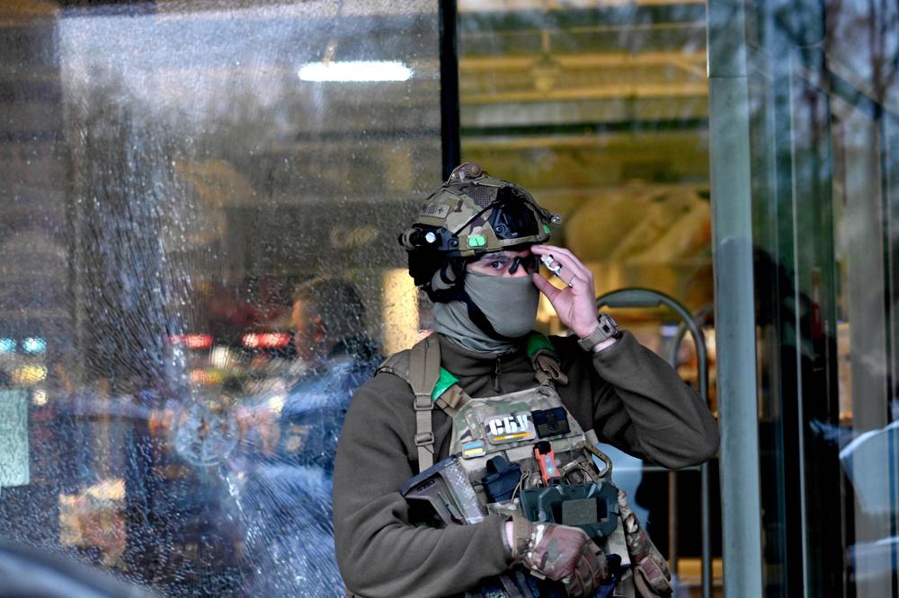 Un policier des forces spéciales se tient devant un impact de balle dans la vitrine d’un supermarché, à la suite d’une fusillade survenue à Kiev, le 18 avril 2026. - SERGEI SUPINSKY / AFP