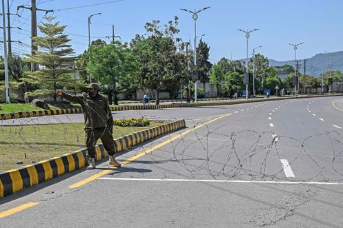 Un agent de sécurité installe des barbelés sur une route fermée dans la « zone rouge » d’Islamabad, le 19 avril 2026. 