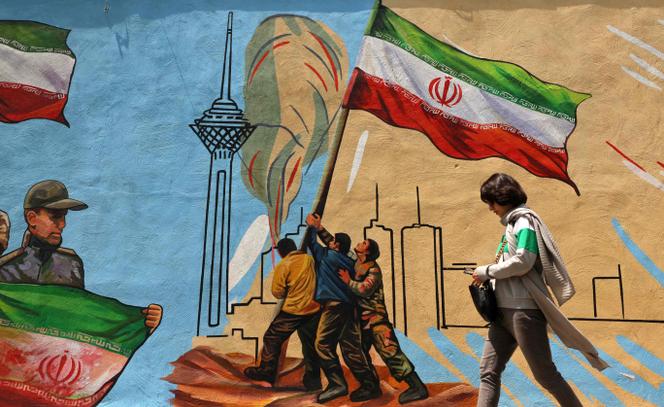 Une Iranienne passe devant une fresque murale anti-américaine et anti-israélienne, à Téhéran, pendant le cessez-le-feu, le 21 avril 2026.