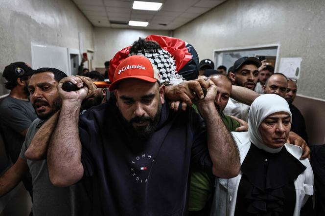 Pessoas em luto carregam o corpo de Awda Atef Awawdeh, uma palestina de 25 anos morta por tiros atribuídos a colonos israelenses, em Deir Dibwan, Cisjordânia, para um hospital em Ramallah, 22 de abril de 2026.