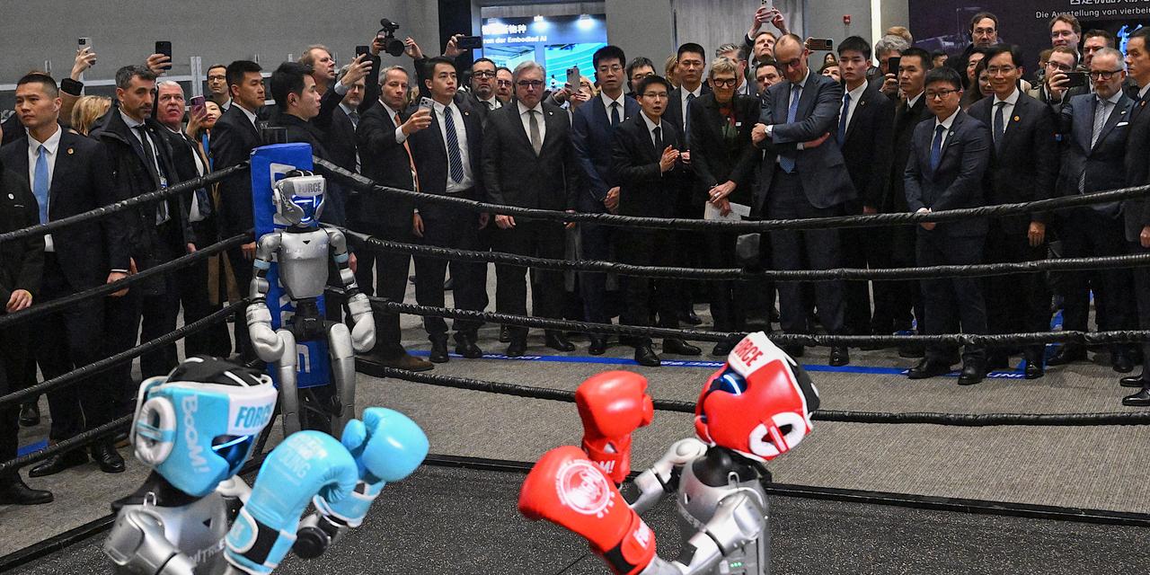 German Chancellor Friedrich Merz (back centre R), accompanied by Unitree Robotics CEO Wang Xingxing (back centre L), watches robot boxing at a showroom of Unitree Robotics products in Hangzhou, in eastern China’s Zhejiang Province on February 26, 2026. Merz arrived in the Chinese tech hub of Hangzhou on February 26 with a large group of entreprenuers, hoping to land new contracts a day after meeting President Xi Jinping and announcing an Airbus deal. (Photo by Jade Gao / AFP)