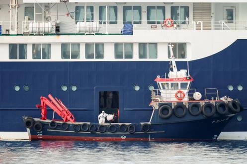 Une personne portant un équipement de protection individuelle récupère un colis provenant du paquebot MV « Hondius », dans le port de Granadilla de Abona, à Tenerife, dans l’archipel des Canaries, en Espagne, le 10 mai 2026. 