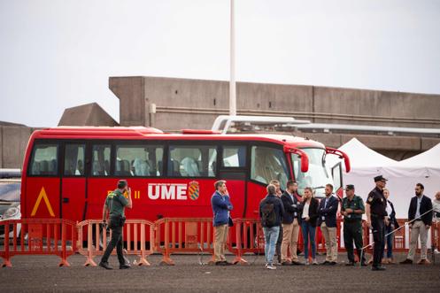 Des officiels se tiennent près d’un bus militaire qui servira à transférer les personnes évacuées du MV « Hondius », dans le port industriel de Granadilla de Abona, sur l’île de Tenerife, en Espagne, le 10 mai 2026. 