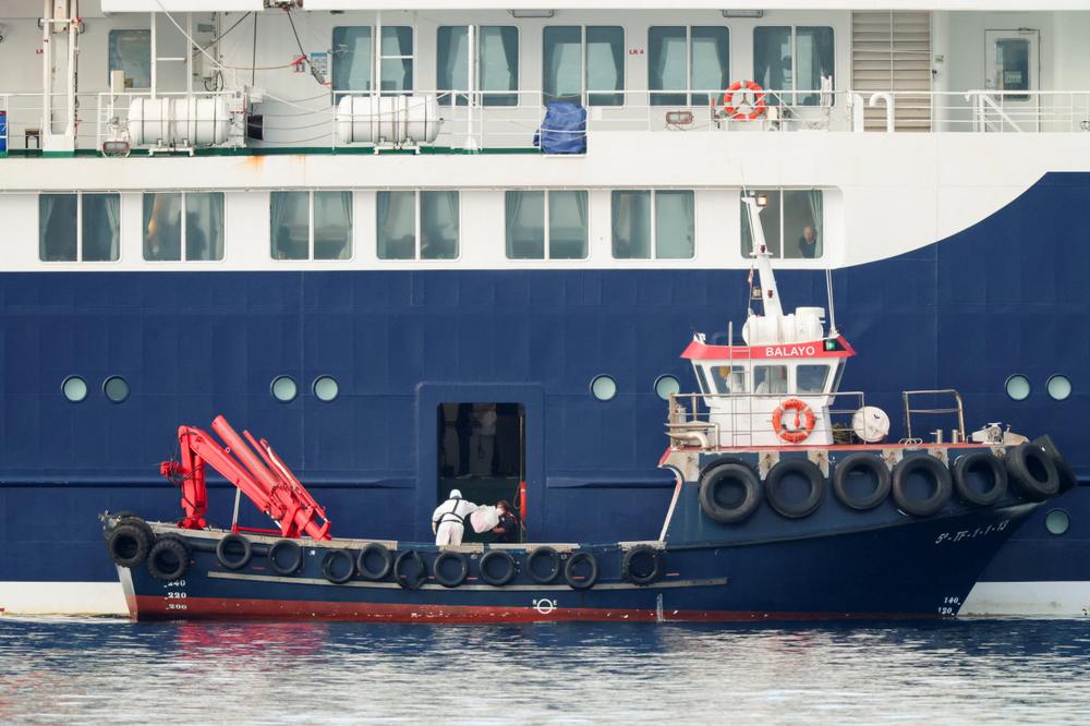 Une personne portant un équipement de protection individuelle récupère un colis provenant du paquebot MV « Hondius », dans le port de Granadilla de Abona, à Tenerife, en Espagne, le 10 mai 2026. - HANNAH MCKAY / REUTERS
