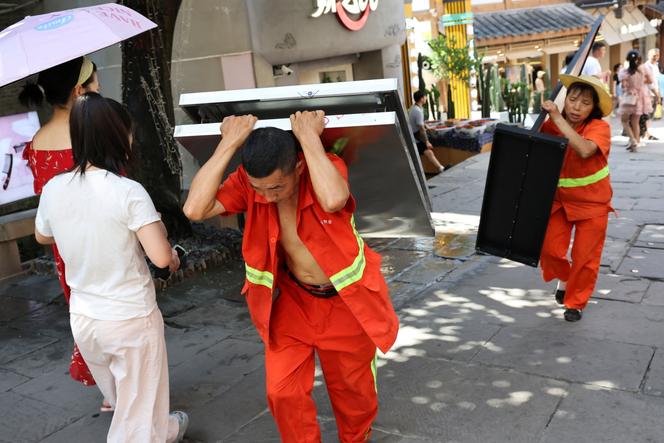 Des ouvriers transportent des panneaux d’information à Chongqing (Chine), le 31 juillet 2025.
