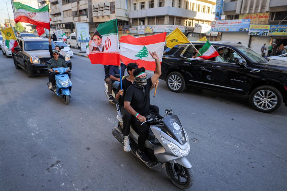 Des manifestants brandissent des drapeaux aux couleurs de l’Iran, du Liban et du Hezbollah, dans une rue de Bagdad (Irak), pour célébrer l’accord-cadre conclu le 15 juin 2026. - AHMAD AL-RUBAYE / AFP