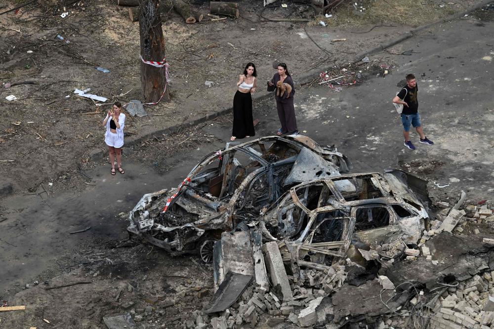 Des habitants examinent des voitures calcinées garées devant un immeuble résidentiel endommagé après une attaque aérienne russe sur Kiev, la capitale ukrainienne, le 3 juillet 2026. - SERGEI SUPINSKY/AFP
