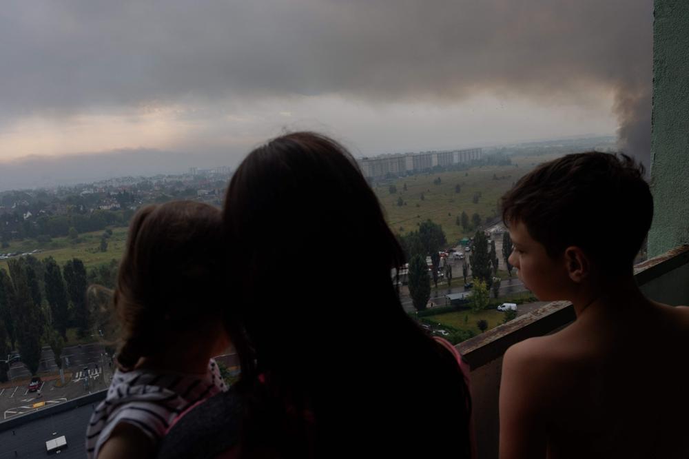 Une famille ukrainienne observe un incendie déclenché par des frappes russes, à Kiev, le 5 août 2026. - TETIANA DZHAFAROVA/AFP