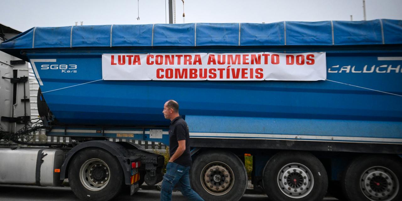 A man walks past a truck with a sign reading "fight against fuel price increases" as truck drivers take part in a go-slow convoy to protest against the rising of fuel prices in Lordelo, near Pacos de Ferreira, northern Portugal on September 25, 2026. (Photo by MIGUEL RIOPA / AFP)