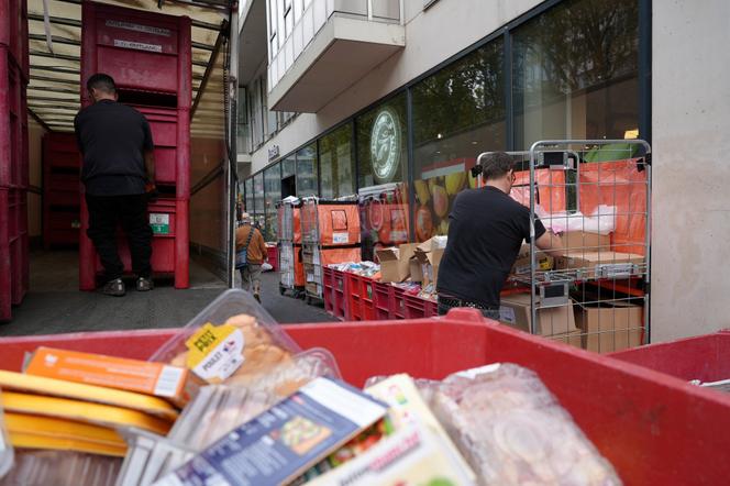 Des employés remplissent des cartons de denrées avariées devant un supermarché, après la cyberattaque ayant visé les systèmes de réfrigération de plusieurs enseignes. A Paris, le 13 octobre 2026. - LUCIEN LIBERT/REUTERS