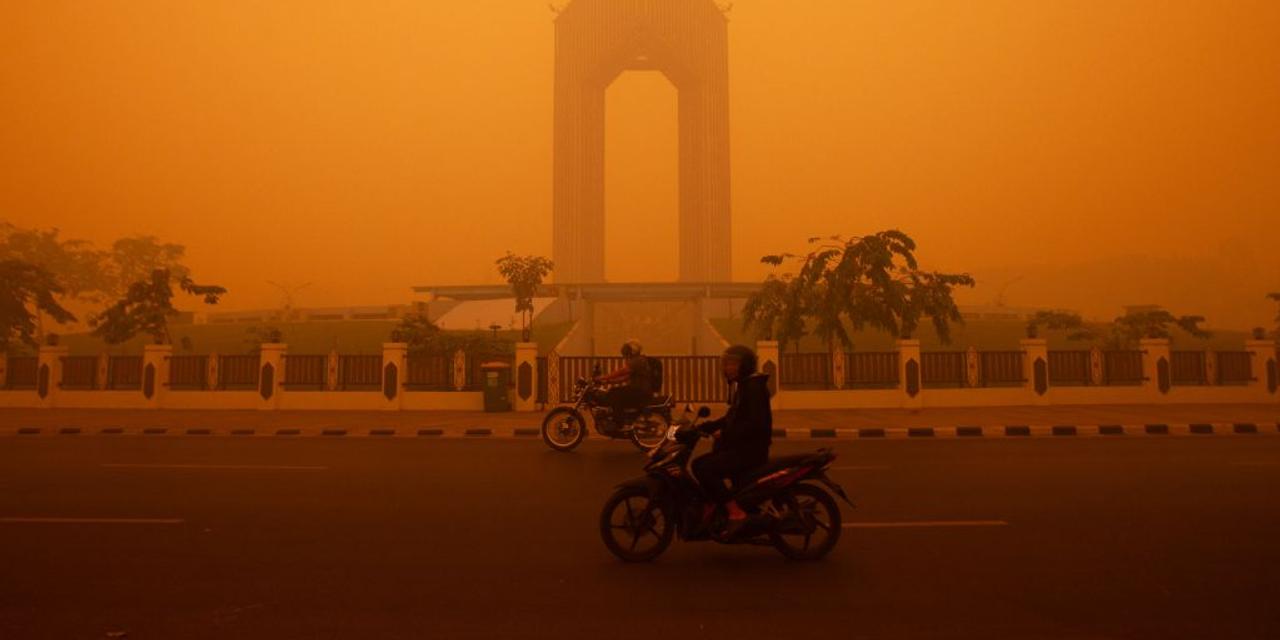 Motorcyclists ride in the morning in Palangkaraya, Central Kalimantan on October 14, 2026, amid thick haze from forest and land fires in the region. Toxic haze has shrouded parts of Indonesia, Malaysia and Singapore for weeks as Jakarta struggles to contain fires that have scorched large tracts of Borneo and Sumatra, with the smoke drifting across the region. (Photo by REINA / AFP)