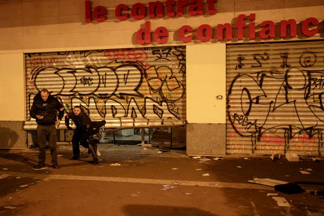 Deux policiers arrêtent un jeune homme qui se trouvait dans le Darty du boulevard de Belleville, à Paris, dans la nuit du 18 au 19 octobre 2026. - ADRIENNE SURPRENANT/MYOP POUR « LE MONDE »