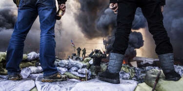 Anti-government demonstrators stand on barricades during clashes with riot police in Kiev on February 18, 2014. Opposition leader Vitali Klitschko on February 18 urged women and children to leave the opposition's main protest camp on Kiev's Independence Square, known as Maidan, as riot police massed nearby. "We ask women and children to quit Maidan as we cannot rule out the possibility that they will storm (the camp)," the former heavyweight boxing champion told protestors on the square.    AFP PHOTO / SANDRO MADDALENA