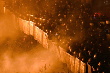 Riot police face anti-government protesters during clashes during the storming of Independence Square in Kiev on February 18, 2014. Flames engulfed the main anti-government protest camp on Kiev's Independence Square as riot police tried to force demonstrators out following the bloodiest clashes in three months of protests. The iconic square turned into a war zone as riot police moved slowly through opposition barricades from several directions, hurling stun grenades and using water cannon to clear protestors.    AFP PHOTO/SERGEI SUPINSKY