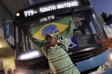 A man holding a Brazilian national flag stands in front of a bus during a protest demanding improvements be made to the public transport system, at the bus station in the centre of Brasilia June 19, 2013. This month's transport fare hikes, which came as Brazil struggles with annual inflation of 6.5 percent, stirred a groundswell of other complaints, leading to the biggest protests to sweep Brazil in more than two decades.   REUTERS/Ueslei Marcelino (BRAZIL - Tags: POLITICS CIVIL UNREST TRANSPORT BUSINESS)