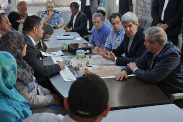 U.S. Secretary of State John Kerry (2nd R) greets a group of Syrian refugees during a joint meeting with Jordanian Foreign Minister Nasser Judeh (sitting, R) at the Zaatari refugee camp near the Jordanian city of Mafraq July 18, 2013. REUTERS/Mandel Ngan/Pool (JORDAN - Tags: POLITICS)