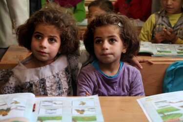 Twin sisters, who fled the fighting in Syria with their family, sit at their desks at the UNICEF school, during a visit by the Italian foreign minister, Emma Bonino to the Zaatari refugee camp near the Syrian border, in Mafraq, Jordan, Tuesday, June 25, 2013.  (AP Photo/Mohammad Hannon)