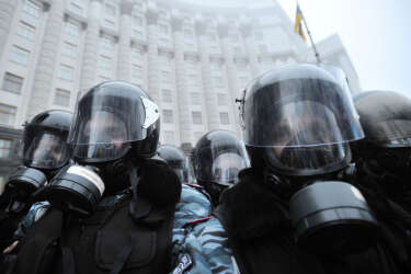 Riot police wear gas masks as they block protesters in front of Cabinet of Ministers of Ukraine during a rally in Kiev on November 24, 2013. Thousands of pro-Europe protesters in Ukraine attempted to storm the government building in the capital of Kiev Sunday, clashing with police who fired tear gas to keep them back. Protesters tried to break through police ranks surrounding the building, with some throwing stones and hitting officers with the signs they were carrying, as police fought back with batons, an AFP correspondent reported. AFP PHOTO / GENYA SAVILOV
