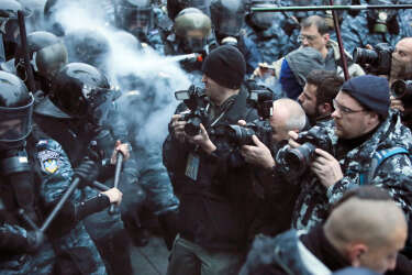 Photographers take photos during a fight between opposition protesters and riot police in front of the Ukrainian Cabinet of Ministers in Kiev, Ukraine, Sunday, Nov. 24, 2013. Tens of thousands of demonstrators demand that the Ukrainian government reverse course and sign a landmark agreement with the European Union in defiance of Russia. The protest was the biggest Ukraine has seen since the peaceful 2004 Orange Revolution, which overturned a fraudulent presidential election result and brought a Western-leaning government to power. (AP Photo/Efrem Lukatsky)