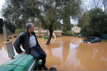 A man brings another man back to his house with the help of a tractor as the house is surrounded by floodwaters after heavy rainfall the previous days, in Hyeres, on January 19, 2014. The Orange alert announced by French authorities in reponse to heavy rainfall and floods in southern France has been lifted today in the Bouches-du-Rhone region but maintained until tomorrow in the Var. AFP PHOTO / ANNE-CHRISTINE POUJOULAT