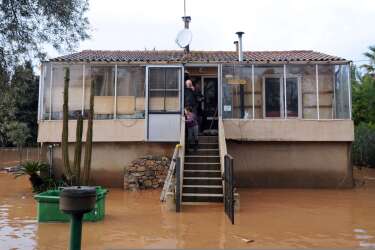 People stand on the steps of their house surrounded by floodwaters after heavy rainfall the previous days, in Hyeres, on January 19, 2014. The Orange alert announced by French authorities in reponse to heavy rainfall and floods in southern France has been lifted today in the Bouches-du-Rhone region but maintained until tomorrow in the Var. AFP PHOTO / ANNE-CHRISTINE POUJOULAT