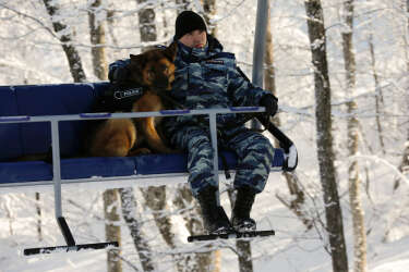 A Russian police officer holds his dog tight as they travel on a ski lift along the Alpine Skiing course of the Sochi 2014 Winter Olympic Games in the Rosa Khutor mountain resort February 2, 2014. Sochi will host the 2014 Winter Olympic Games from February 7 to 23.   REUTERS/Wolfgang Rattay (RUSSIA - Tags: SPORT OLYMPICS SKIING)