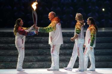 Russian wrestler Alexander Karelin, second from left, hands the torch to Russian gymnast Alina Kabaeva, left,  as Russian tennis player Maria Sharapova, second from right, and Russian pole vaulter Yelena Isinbayeva look on during the opening ceremony of the 2014 Winter Olympics in Sochi, Russia, Friday, Feb. 7, 2014. (AP Photo/Mark Humphrey)