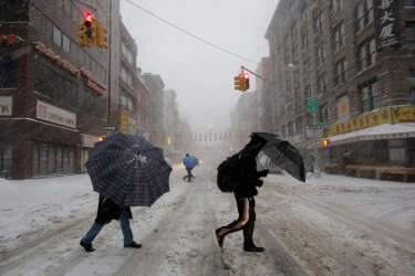 Pedestrians use umbrellas as they walk through falling snow in the Chinatown neighborhood of New York, Thursday, Feb. 13, 2014. Snow and sleet are falling on the East Coast from North Carolina to New England a day after sleet, snow and ice bombarded the Southeast. (AP Photo/Mark Lennihan)
