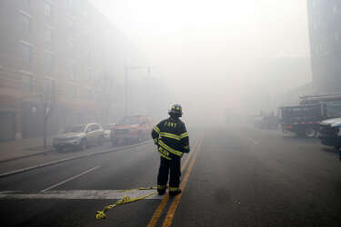 A firefighter stands in smoke filled East 116th street near an apparent building explosion fire and collapse in the Harlem section of New York City, March 12, 2014. A building collapsed in a largely residential block of Upper Manhattan on Wednesday and the New York City Fire Department was searching for anyone trapped in the debris, officials said.  REUTERS/Mike Segar   (UNITED STATES - Tags: DISASTER)