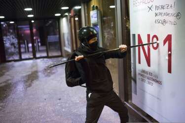 A demonstrator smashes the front of a bank office during a protest against the government in Madrid, Spain, Saturday, March 22, 2014. Spanish police and protesters clashed during an anti-austerity demonstration that drew tens of thousands of people to central Madrid on Saturday. Police said in a statement six officers were injured and 12 people were arrested. (AP Photo/Andres Kudacki)