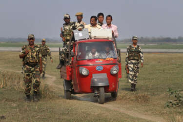 A polling officer carrying electronic voting machines arrives accompanied by security men in a three wheeler on the eve of parliamentary elections at Misamora Sapori, an island in the River Brahmaputra in Assam state, India, Sunday, April 6, 2014. India will hold national elections from April 7 to May 12, kicking off a vote that many observers see as the most important election in more than 30 years in the world's largest democracy. (AP Photo/Anupam Nath)