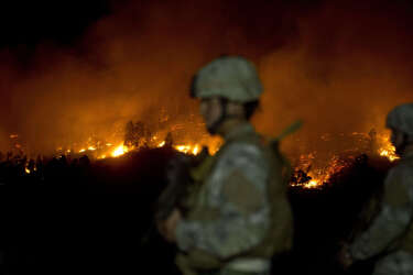 Chilean soldiers patrol next to a fire after some focuses reactivated, in Valparaiso, Chile, on April 13, 2014. More than 10,000 people were evacuated as an army of firefighters battled a killer blaze that --on the eve-- tore through parts of Chile's historic port of Valparaiso and left at least 11 people dead. The fire, which started in woodland Saturday, gutted 500 homes as flames advanced on the city of 270,000, famed for its UNESCO-listed center with cobblestone streets and brightly painted wooden homes. AFP PHOTO/MARTIN BERNETTI