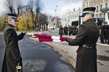 Deux soldats lettons roulent le drapeau national après une cérémonie, devant le monument  de la Liberté, à Riga. Ce pays balte de plus de  2 millions d'habitants compte 283 000 citoyens de seconde zone aux droits limités, car russophones. On les apelle parfois les "pieds-rouges". -