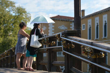 Tourists stand on bridge on which padlocks (locks of love) are hanged on August 29, 2013 in Venice. AFP PHOTO / GABRIEL BOUYS