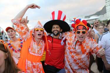 Dutch soccer fans pose for a photo with a Chilean soccer fan, center, while watching the live broadcast of the World Cup match between Spain and the Netherlands, inside the FIFA Fan Fest area on Copacabana beach in Rio de Janeiro, Brazil, Friday, June 13, 2014. The Netherlands thrashed Spain 5-1 Friday. It was a humiliating defeat for the defending World Cup champions. (AP Photo/Leo Correa)