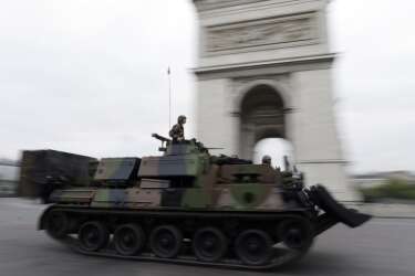French soldiers drive an armoured vehicle past the Arc de Triomphe on the Place de L'Etoile prior to the start of the annual Bastille Day military parade on the in Paris, on July 14, 2014. AFP PHOTO / KENZO TRIBOUILLARD