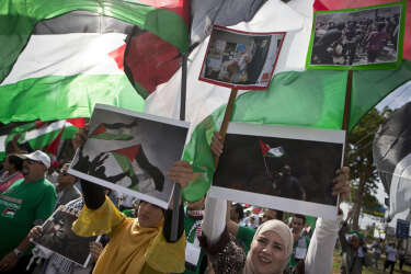 Members of the Palestinian community resident in Nicaragua, hold up Palestinian flags and photos, protesting Israeli air strikes on the Gaza strip, during a demonstration outside the U.N. headquarters in Managua, Nicaragua, Monday, July 14, 2014. (AP Photo/Esteban Felix)