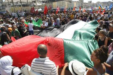 Pro-Palestinian demonstrators hold a giant Palestinian flag, in Marseille, Saturday, July 26, 2014, during a demonstration to protest against the Israeli army's shellings in the Gaza strip. (AP Photo/Claude Paris)