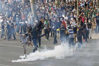 Pro-Palestinian protesters run amid tear gas canisters, as clashes erupted at Place de La Republique during a banned demonstration in support of Gaza, in Paris, France, Saturday, July 26, 2014. A brief cease-fire Saturday in the Gaza war between Israel and Hamas militants allowed thousands to return home to see the destruction. Palestinians walked through the concrete rubble that once used to be homes, collecting what keepsakes they could recover. (AP Photo/Francois Mori )