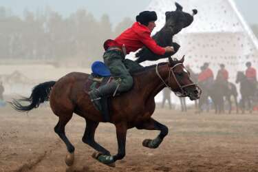 A Kyrgyz rider plays the traditional Central Asian sport Buzkashi also known as Kok-Boru or Oglak Tartis in the first World Nomad Games in Cholpon-Ata, some 270 km from Bishkek on September 11, 2014 . Mounted players compete for points by throwing a stuffed sheepskin into a well.  Teams of Azerbaijan, Kazakhstan, Belarus, Mongolia and Tajikistan take part in the games. AFP PHOTO / VYACHESLAV OSELEDKO