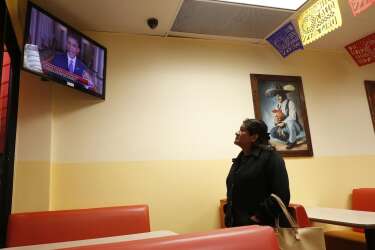 A woman watches U.S. President Barack Obama's White House speech on immigration at a restaurant in Huntington Park, California, November 20, 2014. Obama imposed the most sweeping immigration reform in a generation on Thursday, easing the threat of deportation for about 4.7 million undocumented immigrants and setting up a clash with Republicans. REUTERS/Lucy Nicholson   (UNITED STATES - Tags: POLITICS SOCIETY IMMIGRATION)