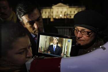 Rosa Lozano, from Washington, left, translates the speech into Spanish as Lita Trejo, from El Salvador, and Texas Democratic State Rep. Ramon Romero, listen to President Obama's speech on a tablet, during a demonstration in front of the White House in Washington, Thursday, Nov. 20, 2014. President Barack Obama announced executive actions on immigration during a nationally televised address. (AP Photo/Alex Brandon)