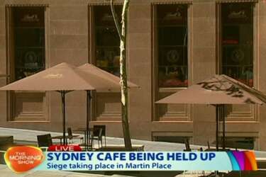 This image taken from video shows people against shop windows holding up hands inside a cafe in Sydney, Australia Monday, Dec. 15, 2014. An apparent hostage situation was unfolding inside the chocolate shop and cafe in Australia's largest city on Monday, where several people could be seen through a window with their hands held in the air. (AP Photo/Channel 7 via AP Video) AUSTRALIA OUT