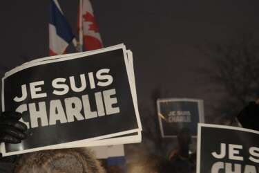 People holds signs reading "I  Am Charlie" during a vigil January 7, 2015 outside  City Hall in Montreal, Canada  for the victims of the shooting at the office of the French satirical magazine Charlie Hebdo.  Twelve people were killed when several gunmen opened fire at Charlie Hebdo's headquarters in Paris, France on January 7th. AFP PHOTO / MARC BRAIBANT