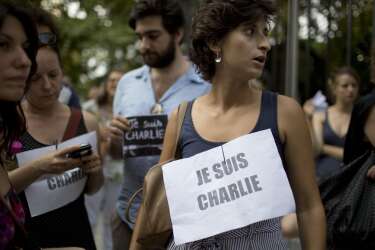 People stand outside France's embassy wearing signs that read in French "I am Charlie" in solidarity with those killed in an attack at the Paris offices of the weekly newspaper Charlie Hebdo in Buenos Aires, Argentina, Wednesday, Jan. 7, 2015. Masked gunmen stormed the the satirical newspaper that caricatured the Prophet Muhammad, methodically killing 12 people Wednesday, including the editor, before escaping in a car. It was France's deadliest postwar terrorist attack. (AP Photo/Natacha Pisarenko)