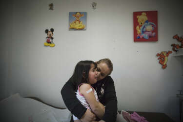 Athens, Greece 2015A young gilr with her mother at the pediatrics unit of the "Doctors of the world".Inside the polyclinic of the human rights organisation Medecins du Monde (Doctors of the World), that provides free primary health care to people who cannot afford those services in Greece, and its patient roster has been growing steadily since the financial crisis struck.
