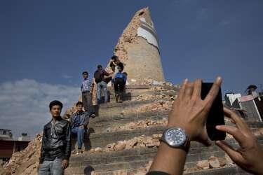 Locals take snapshots with their cell phones at the historic Dharahara Tower, a city landmark, that was damaged in Saturdays earthquake in Kathmandu, Nepal, Monday, April 27, 2015. A strong magnitude earthquake shook Nepals capital and the densely populated Kathmandu valley on Saturday devastating the region and leaving tens of thousands shell-shocked and sleeping in streets. (AP Photo/Bernat Armangue)
